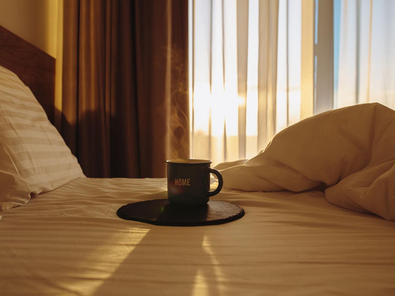 Cup Of Coffee In Bed At Sunrise. Dawn With A Cup Of Coffee In Bed. Hot Coffee In Bed. Waking Up With