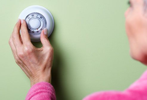 16getty rf photo of woman adjusting thermostat