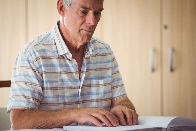 bigstock Senior man using braille to re 137937704