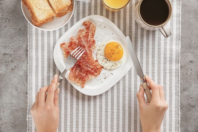 bigstock Young woman eating fried egg a 216895150