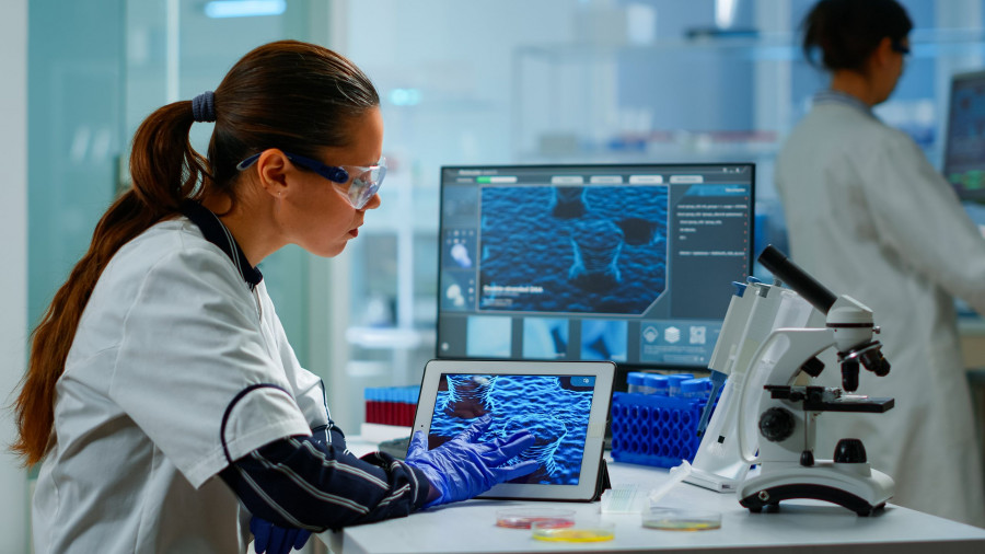 Scientist Using Digital Tablet Analysing Virus Evolution, Treatment Development In Medical Research