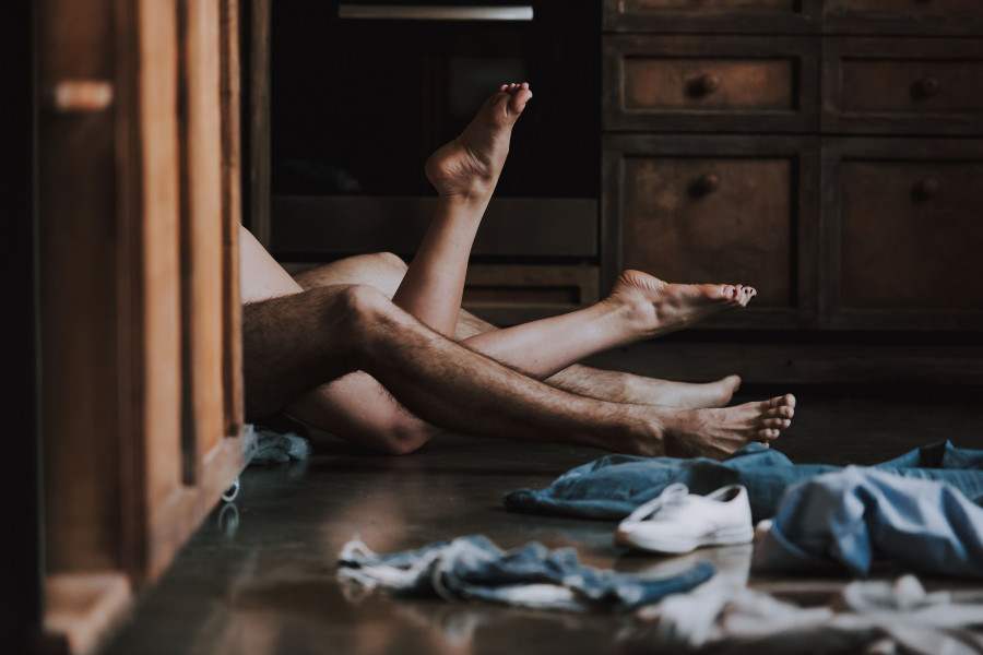 Attractive Passionate Couple Having Sex In Kitchen. Man And Woman Lying On The Floor In The Kitchen