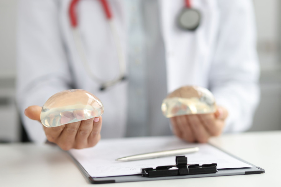 Doctor Plastic Surgeon Holds Silicone Breast Implants. Breast Augmentation And Lift Concept