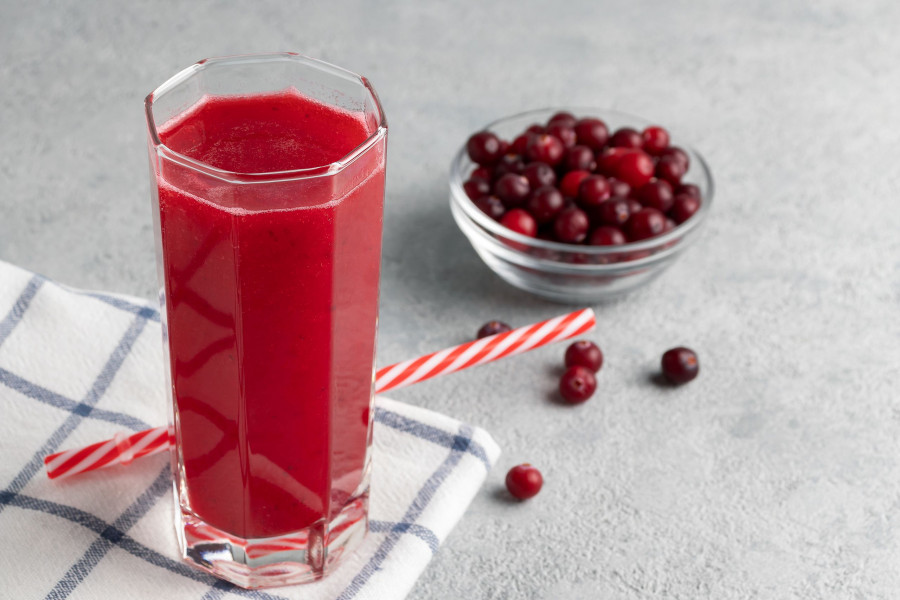 One Glass With Homemade Freshly Cranberry Juice And A Bowl Of Cranberries On A Gray Concrete Table